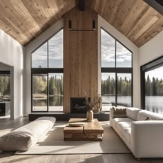 a large living room with wooden ceilings and windows on the side, along with white couches