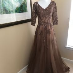 Beautiful, Flowing Cocoa Colored Gown For Any Special Occasion Delicately Embroidered Floral Pattern With Small Rhinestones For Glimmer Full Multi Layered Bottom Features: Deep V Neck, Hidden Back Zipper, Sheer Sleeve, Built In Bodice Support Size 6 Measures: 16" Underarm To Underarm, 30" Waist, 16" Sleeve From Shoulder 60" Long From Shoulder To Hem Formal A-line Gown With Floral Embroidery, Embroidered Fitted Ball Gown Evening Dress, Festive A-line Gown For Formal Occasions, Embroidered Fitted A-line Evening Dress, Festive A-line Formal Gown, Embellished Lace Mother Of The Bride Dress, Formal Embroidered Evening Dress With Fitted Bodice, Formal Evening Dress With Floral Embroidery And Fitted Bodice, V-neck Embellished Gown For Mother Of The Bride