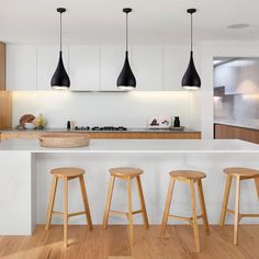 three wooden stools sit in front of an island