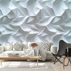 a living room filled with furniture and walls covered in white paper origami shapes