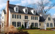 a large white house with black shutters on the front and side windows is shown