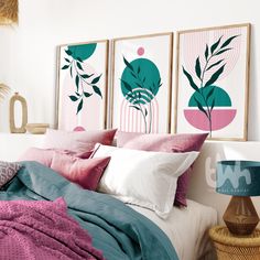 a bed with pink and green pillows on top of it next to two framed pictures