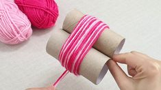 someone is knitting yarn on top of two rolls of twine with pink and white stripes