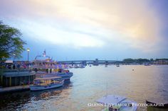 several boats are docked on the water at dusk in front of an overcast sky