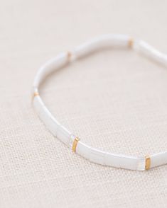 Handcrafted stretch bracelet made with delicate glass colored Tila beads and accented with 24k gold plated Tila beads. Designed in sunny Florida, made by artists in the USA. 6.5 inches, fits most, fit similar to friendship bracelet or a hair tie, not intended to be a bangle bracelet. Dainty White Stretch Bracelet With Gold Beads, Gold And Heishi Beads Stretch Bracelet Gift, Gift Stretch Bracelet With Gold And Heishi Beads, Adjustable Tiny Beads Stretch Bangle Bracelet, Adjustable Tiny Beads Stretch Bangle, White Stretch Bracelet With Gold Beads As Gift, Dainty White Stretch Bracelet With Spacer Beads, Adjustable White Dainty Stretch Bracelet, White Adjustable Dainty Stretch Bracelet