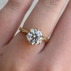 a woman's hand with a diamond ring on top of her finger, showing the center stone