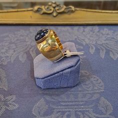 This Ring in 18k Gold with an Iolite makes a beautiful addition to any jewelry collection. The warm color of the 18k gold holds the mesmerizing Iolite for a stunning contrast. A true show stopper, this beautiful and unique ring is sure to turn heads. Formal Yellow Gold Cabochon Sapphire Ring, Luxury 14k Gold Sapphire Ring Hallmarked, Luxury 14k Gold Sapphire Ring With Hallmark, Luxury Tanzanite Yellow Gold Ring, Luxury Gold Amethyst Ring With Bezel Setting, Luxury Yellow Gold Tanzanite Ring, Luxury Hallmarked Yellow Gold Sapphire Ring, Luxury 14k Gold Moonstone Ring For Formal Occasion, Luxury 14k Gold Moonstone Ring For Formal Events