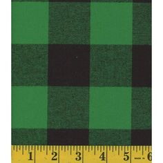 a green and black plaid fabric with a ruler on the bottom right hand side that says,