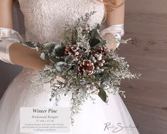 a woman in a white wedding dress holding a bouquet of pine cones and greenery