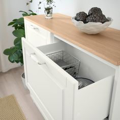 a bowl of fruit sitting on top of a wooden counter next to a white cabinet