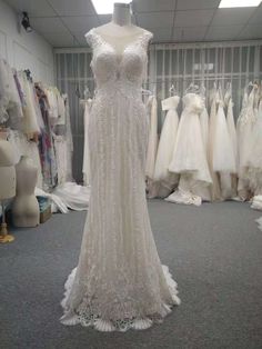 a wedding dress on display in a bridal shop with other dresses and gowns