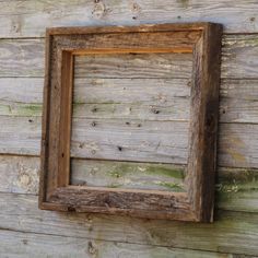 an old wooden frame hanging on the side of a wall with wood planks around it