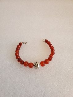 "This handmade Genuine Carnelian Beaded Bracelet was made on Silver Wire with round Genuine Carnelian Ball Beads. The bracelet is closed off using a 925-lobster clasp and jump ring. At the center is medium size Silver Ornate Metal Ball that is the focal point. This bracelet was handmade by Dulcinea for a small wrist and all items used are new. This bracelet would be a great gift and will arrive in a gift box with FREE SHIPPING. Measure: 6 5/8\" L Material: Genuine Carnelian in Round Shape, 925 L Red Carnelian Beaded Bracelets With Round Beads, Red Carnelian Beaded Bracelet With Round Beads, Red Carnelian Round Beads Bracelet, Carnelian Round Beads Bracelet For Gift, Spiritual Amber Bracelets With Polished Beads, Amber Round Beaded Bracelets With Natural Stones, Adjustable Carnelian Bracelet As A Gift, Adjustable Carnelian Bracelet Perfect For Gifts, Red Carnelian Beaded Bracelets