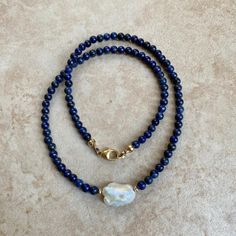 Lapis Lazuli necklace with a freshwater baroque pearl center . Length 16" Lapis is one of the oldest spiritual stones known to man, used by healers, priests and royalty, for power, wisdom and to stimulate psychic abilities and inner vision. It represents universal truth. Throat Chakra. -This information is intended for spiritual support only- Findings 14K GF Beads 4mm FWP 14 x 12mm Spiritual Pearl Necklace With Round Beads, Spiritual Pearl Beaded Necklace With Gemstone, Spiritual Single Strand Beaded Necklace, Baroque Pearl Necklace With Gemstone, Baroque Pearl Necklaces With Gemstone Round Beads, Spiritual Pearl Necklace With Natural Stones, Spiritual Single Strand Pearl Necklaces, Spiritual Beaded Necklace With Pearl Pendant As Gift, Spiritual Single Strand Necklace For Meditation