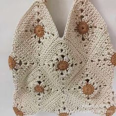 a crocheted bag with flowers on it hanging from a hook in front of a white wall