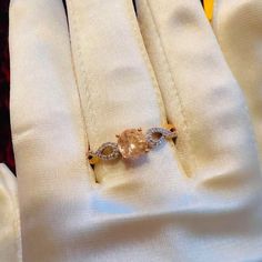 an engagement ring is sitting on top of a white shirt with yellow and brown accents