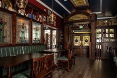 the interior of a restaurant with wooden tables and green chairs, stained glass windows, and wood paneled walls