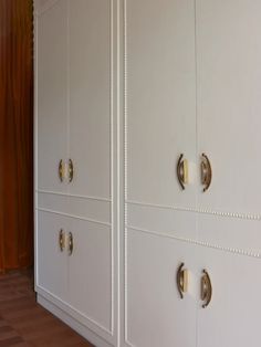 two white cupboards with brass handles and knobs on the doors are next to each other