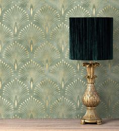 a gold lamp sitting on top of a wooden table next to a green wallpaper