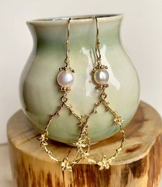 Enhance your boho chic style with this set of long gold teardrop-shaped flower branch dangly earrings. Featuring large gold-plated brass flower branch charms, these earrings are delicately crafted and exude a sweet charm. The handmade earring hooks, crafted with 10K gold-filled wire, add a touch of elegance. At the top, white freshwater pearls with gold-plated floral bead caps provide a classic and timeless accent. Measuring 2 1/2" X 7/8", including the gold-filled wire hooks, these earrings are Bridal Pearl Earrings, Branch Earrings, Bridal Earrings Pearl, Handmade Earring, Boho Chic Style, Flower Branch, White Freshwater Pearl, Dangly Earrings, Bridal Pearls