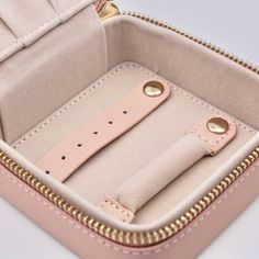 the inside of a pink case with gold hardwares and two watch straps in it