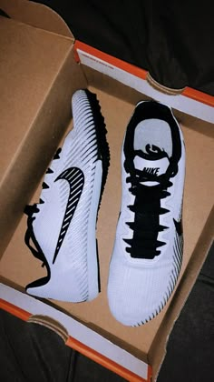 a pair of white and black nike shoes in a box on the floor next to a shoe brush