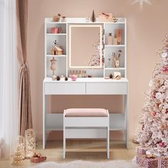 a white dressing table with a mirror and stool next to a pink christmas tree in the corner