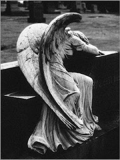 black and white photograph of an angel sitting on a bench