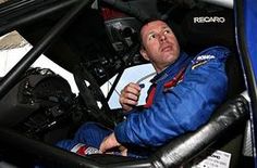 a man sitting in the cockpit of a race car looking up into the sky with his hands on his chin