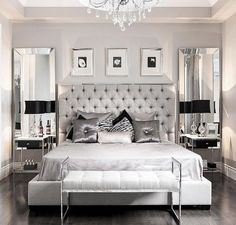 a bedroom with a bed, mirror and chandelier in black and white colors