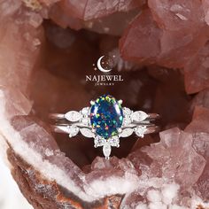 a ring with an oval blue opal surrounded by white diamonds on top of some rocks