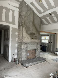 an unfinished room with a brick fireplace in the middle and white paint on the walls