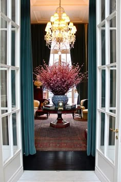 an open door leading to a living room with chandelier