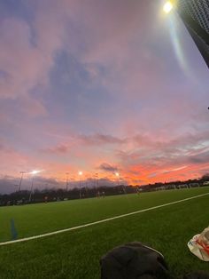 the sun is setting over a soccer field