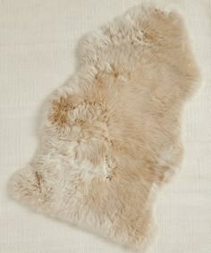 a sheepskin rug is laying on top of a white surface with no one around it