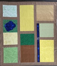 a quilted wall hanging with different colored squares and dots on the bottom, along with a blue piece of fabric