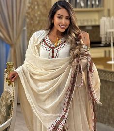 Get this dress for extra luxury for it has a long, flowing design with a modest, and elegant cut. This dress is often worn for special occasions such as religious ceremonies, weddings, or cultural celebrations Material Cotton Thread Estimated delivery : 2weeks to 3weeks Contact WhatsApp +1(304)-306-2784Email: contact@ethiopian.store Traditional Beige Dress With Dabka Work, Beige Dresses With Resham Embroidery In Traditional Drape, Beige Embroidered Dress With Traditional Drape, Long Cream Festive Dress, Traditional Long Beige Dress, Anarkali Tunic Dress With Dupatta, Cream Maxi Dress With Resham Embroidery, White Long Dress With Dabka Work, White Long Dresses With Dabka Work