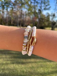 One-of-a-kind! Lightly colored ( pink, white, blue, and gold 🤍.  Lot/Set of 3 handmade bracelets.  Accent Bead : gold glass beads, rocks, and, sea shell charm.  Beads : Clay Beads, Glass Beads, and rocks Size: 7.00 inch diameter  Set: 3 Bracelets Gold Bracelets With Round Beads For Vacation, Gold Beaded Bracelets For Vacation, Adjustable Gold Beaded Shell Bracelets, Gold Beaded Charm Bracelet For Beach, Gold Shell Beaded Bracelets As Gift, Gold Beaded Shell With Ocean-inspired Style, White Ocean-inspired Jewelry With Round Beads, Ocean-inspired Beaded Gold Shell, Ocean-inspired Gold Beaded Shell