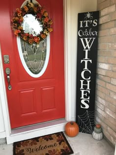 a red front door with a welcome sign next to it and a pumpkin on the doorstep