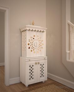 a white cabinet sitting in the corner of a room next to a stair case with gold decorations on it