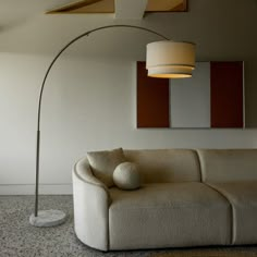 a white couch sitting under a large lamp in a living room