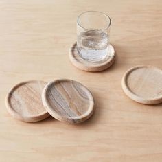 three wooden coasters and a glass on a table