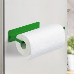 a roll of toilet paper is hanging on the wall next to a green holder that holds two rolls