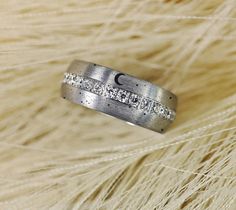 a silver ring with white diamonds on top of some fur and the moon in the background