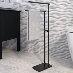 a black towel rack stands next to a white toilet