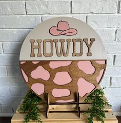 a wooden sign that says hoddy with pink and brown cow spots on it