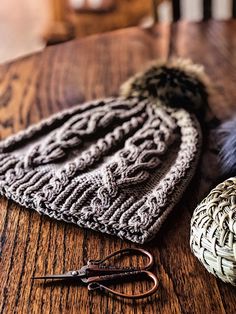 two knitted hats sitting on top of a wooden table