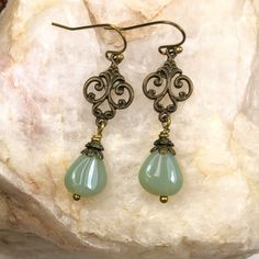 Teardrop beads in opalescent sage green dange from brass filigree.  The intricate filigree charm adds an elegant touch to these green  earrings. High quality Czech glass beads. Trendy green earrings that go with so many colors and styles this season, you'll want this color in your jewelry collection.  Custom earrings: other color beads and metals available.  Bridesmaid earrings can be made in mulitples. Convo me via Etsy with your ideas. Free gift packaging included. Earrings are carded and in an organza bag. Choose your ear wire style at checkout. Hypoallergenic ear wires (nickel and lead free).  Artisan glass beads produced in small quantities in the Czech Republic. Link back to my shop: https://www.etsy.com/shop/JezaJewelry Green Earrings - Teardrop Dangle Glass Beads - Handmade Gift - Hypoallergenic Czech Glass Teardrop Jewelry, Bronze Dangle Teardrop Earrings For Gift, Elegant Czech Glass Teardrop Earrings, Elegant Nickel-free Czech Glass Teardrop Earrings, Elegant Czech Glass Drop Jewelry, Vintage Teardrop Earrings As A Gift, Nickel Free Teardrop Earrings As Gift, Elegant Hypoallergenic Teardrop Beaded Earrings, Vintage Gold Teardrop Beaded Earrings