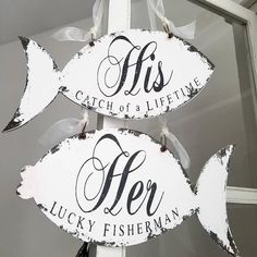 two wooden fish signs hanging from the side of a pole with ribbons on it's sides