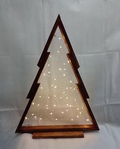 a lighted wooden christmas tree with white lights on the bottom and brown wood base, against a white background